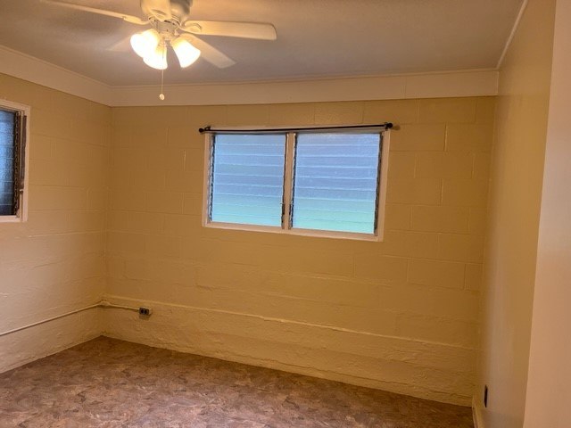 A room with a ceiling fan and a window with blinds.